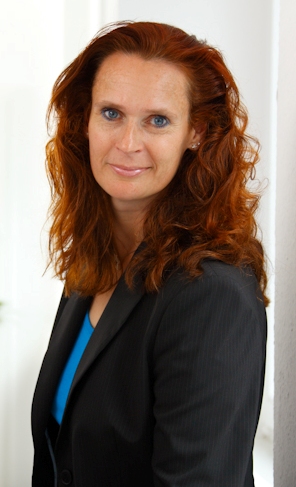 Porträt von Birgit Elstner, einer Versicherungsmaklerin mit rotem Haar und schwarzem Anzug